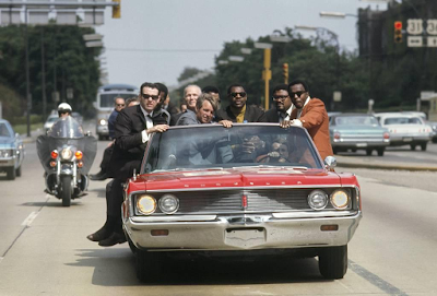 photo of Bobby Kennedy in red car as he campaigns in Indiana during May of 1968, with various aides and friends: former prizefighter Tony Zale and (right of Kennedy) N.F.L. stars Lamar Lundy, Rosey Grier, and Deacon Jones by Bill Eppridge