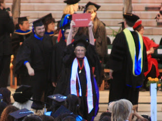 Graduating student holds diploma over her head