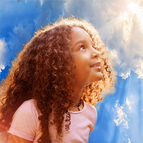 Foto: Afro american happiness little girl with curly hair receives miracle sun rays from the sky