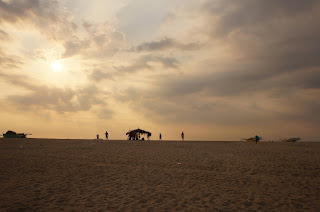 Sunset from the beach with huts and people on the horizon