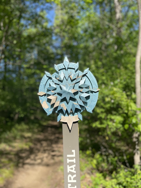 The Carolina Thread Trail sign. It looks like a snowflake on a pole. It is a frosty blue color.