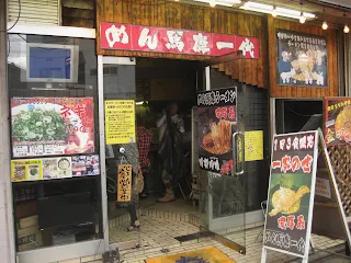 store front of a restaurant in Kyoto Japan with red sign above the door and many posters showing food with Japanese writing on them