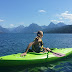 Girl looking at the mountains in her green kayak