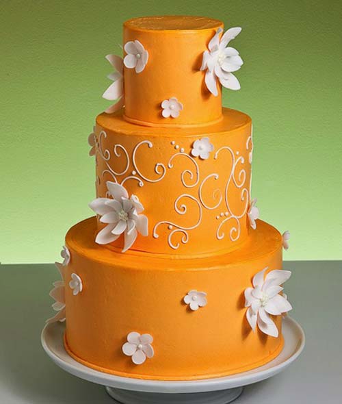 Three tier deep orange round wedding cake with white flowers and a white 