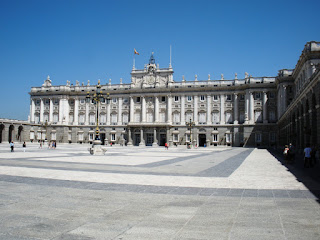 Una gran plaza se abre frente a la fachada sur del palacio, con arcadas a los lados.