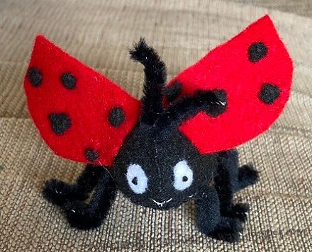 A small stuffed ladybug made of felt with its wings spread open.