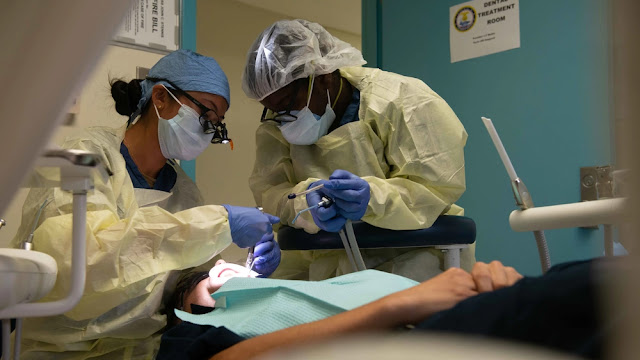 U.S. Navy Lieutenant Tanya Mullin, left, from Virginia Beach, Virginia, Dental Officer assigned to Medical Department onboard the aircraft carrier USS John C. Stennis (CVN 74), and Hospitalman Dimya Heppard, right, from Atlanta, assigned to the ship, perform routine dental cleaning appointment for Interior Communications Electrician Seaman David Boat, from Huntsville, Arkansas, on the floating accommodation facility, in Newport News, Virginia, Aug. 25, 2021. John C. Stennis is in Newport News Shipyard working alongside NNS, NAVSEA and contractors conducting Refueling and Complex Overhaul as part of the mission to deliver the warship back in the fight, on time and on budget, to resume its duty of defending the United States. (U.S. Navy photo by Mass Communication Specialist 3rd Class Daniel Tillie)