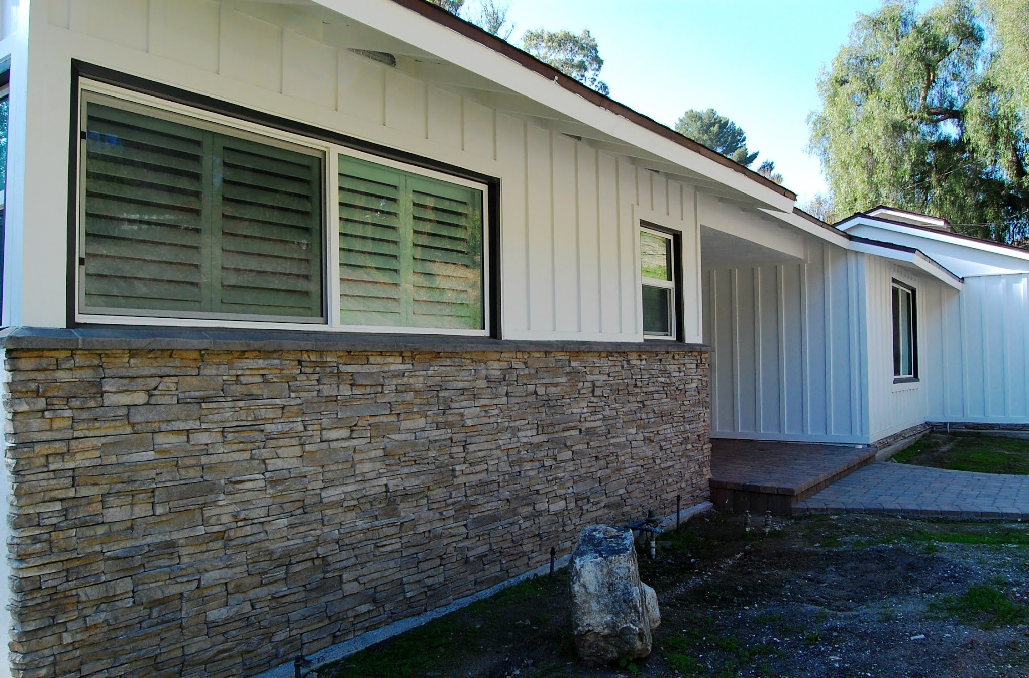 mid-century ranch house exterior home remodel and improvements pavers stone black craftsman entry door board and batten black and white