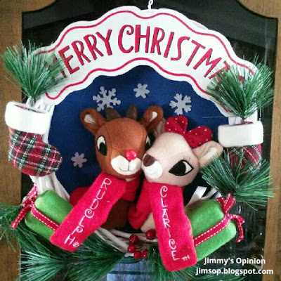 A Christmas wreath with Rudolph the rednosed reindeer and Clarice in the middle and the words Merry Christmas at the top