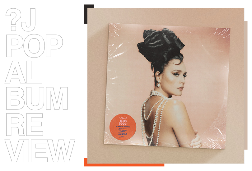 A vinyl of Jessie Ware’s ‘That! Feels Good!’ laid on a light brown surface.  The cover art features a shot of Jessie Ware topless, with pearls hanging down her back and her hair in an up-do with large ringlets.