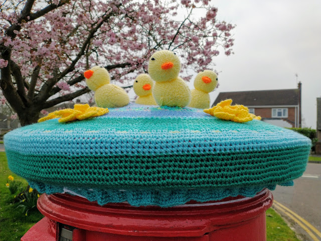 Knitted postbox cover with Easter chicks and spring daffodils