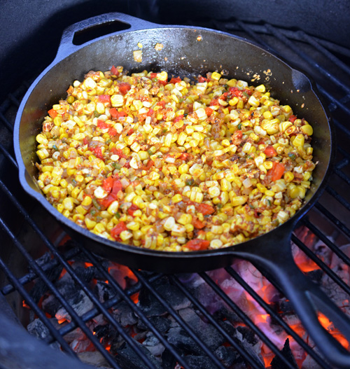 corn and peppers in a cast-iron skillet on the grill