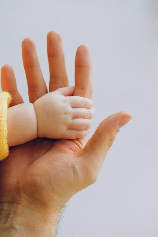 A father holding baby's hand