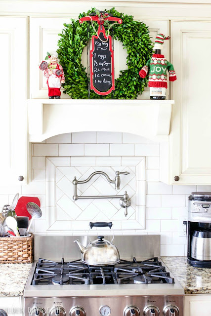 Boxwood wreath with decorative chalkboard wreath for Christmas on kitchen mantel