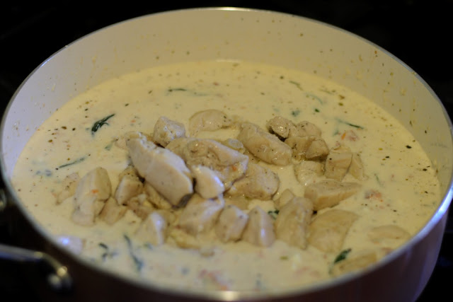 The cooked chicken being added to the pan. 