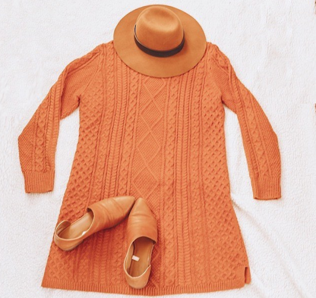 A flatlay of a brown panama hat, a burnt orange sweater dress and brown d'orsay flats.