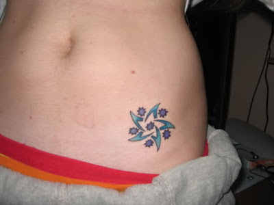 A hibiscus flower on the shoulder blade perhaps a cherry blossom tattoo on