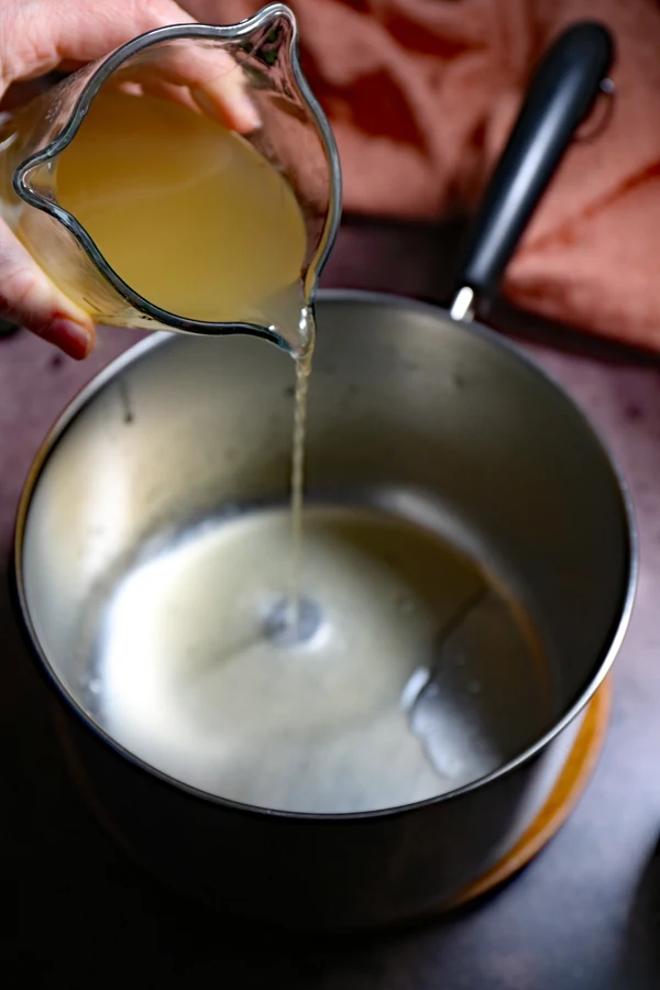 Step-by-step process of making cowboy candy: Apple cider vinegar being poured into a pot