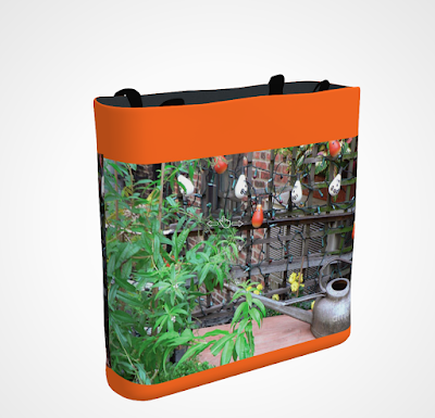 This screen-shot features an orange tote/bag/pouch which has an image imprinted on it. The picture was taken in my garden when decorated for Halloween. It shows Halloween-themed outdoor lights hanging on a wooden trellis. The tote/bag/pouch is available in three sizes (13" by 13", 16" by 16" and 18" by 18") and can be purchased via Fine Art America@ https://fineartamerica.com/featured/halloween-in-the-garden-patricia-youngquist.html?product=tote-bag  TITLE TEXT: My “Halloween in the Garden” tote/bag/pouch is available for purchase via Fine Art America @ https://fineartamerica.com/featured/halloween-in-the-garden-patricia-youngquist.html?product=tote-bag