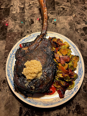 Rare grilled tomahawk ribeye, baked potato and maple bacon Brussels sprouts