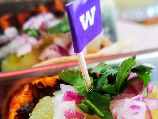 Close up image of the Gluten Free Grilled Halloumi Tacos available at Wahaca, Southbank. Image shows a close up of the halloumi filling, chopped red onion, pineapple salsa and fresh coriander. There is a purple flag in the dish indicating it's gluten free.