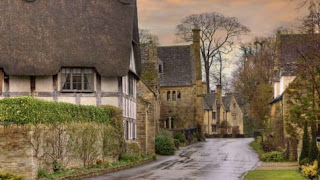 An English Victorian street showing thatched-roof houses.