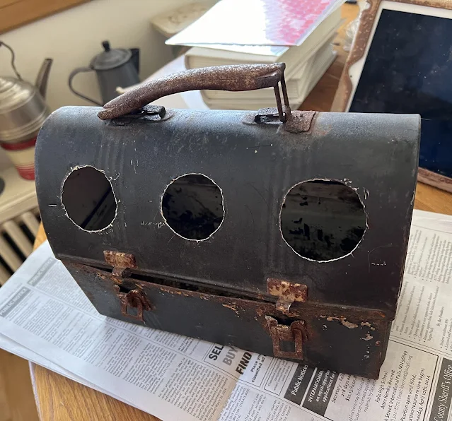 Photo of a vintage metal lunchbox with three round holes.