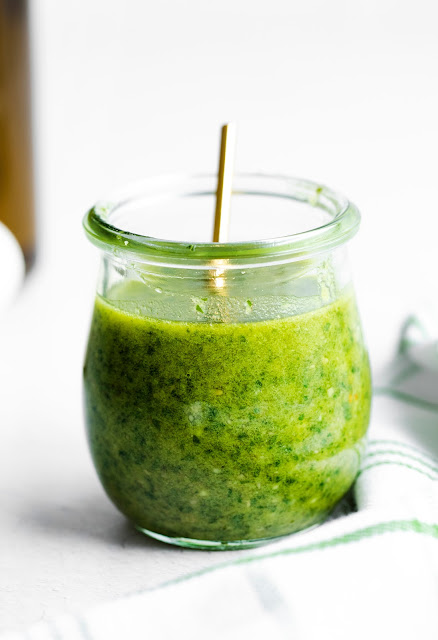 Homemade Pesto in a jar with a gold spoon inside.