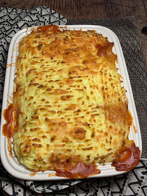 Cheesy Mashed Potato and Bean Bake in a casserole dish on a dark wood table