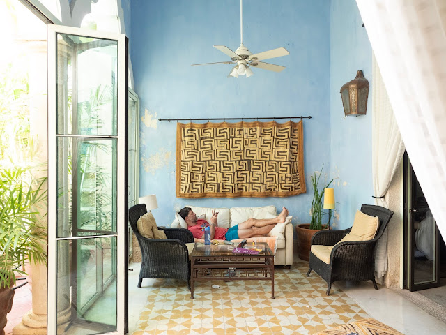 Hombre tumbado en un sofá en una de estar con suelos amarillos y pared azul