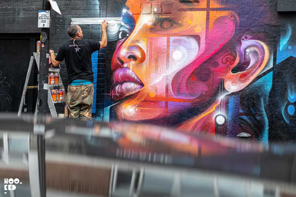 Brick Lane Street Art - Artist Mr Cenz at work on a mural on Bacon Street, London