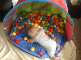 baby in tent with lot of different coloured balls