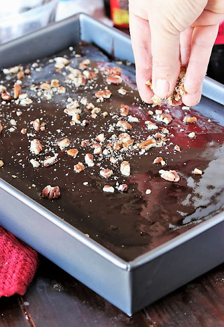 Sprinkling Chopped Pecans on Top of Cheerwine Chocolate Cake Image