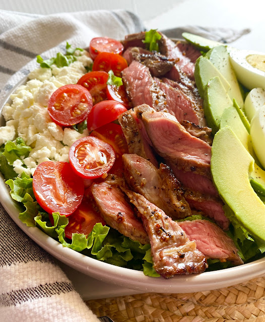 Close up of steak cobb salad in a grey bowl on a placement