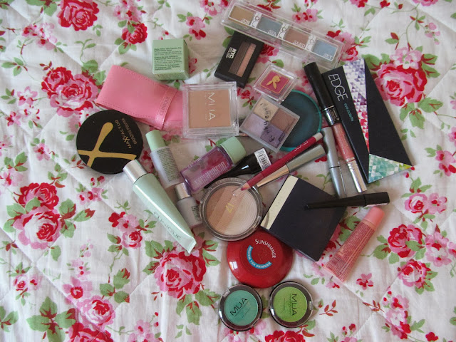 mess of makeup products on floral duvet background