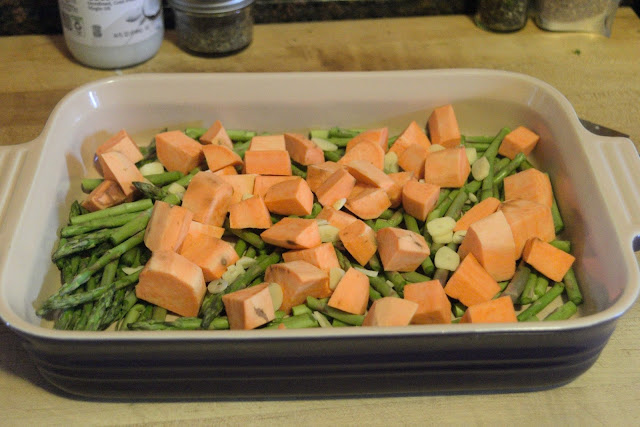 Sweet potatoes and garlic being added to the baking dish.