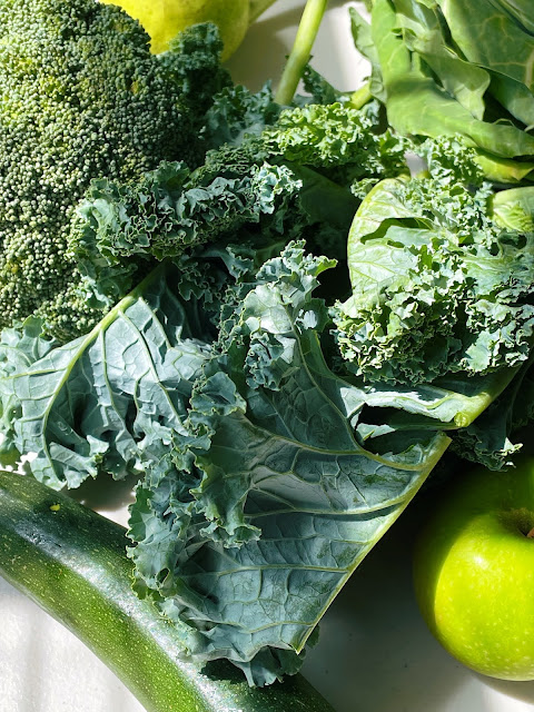 a close up photo of green vegetables, apple, broccoli, collard greens and kale