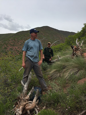 Eric Hipke (S. Canyon SME) speaking to staff ride participants on the west flank fireline with Storm King Peak and Conference Group Leader Zuri Betz (Rocky Mountain Fire Department) in the background.