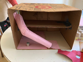 diorama box on a table with a pink tube slide