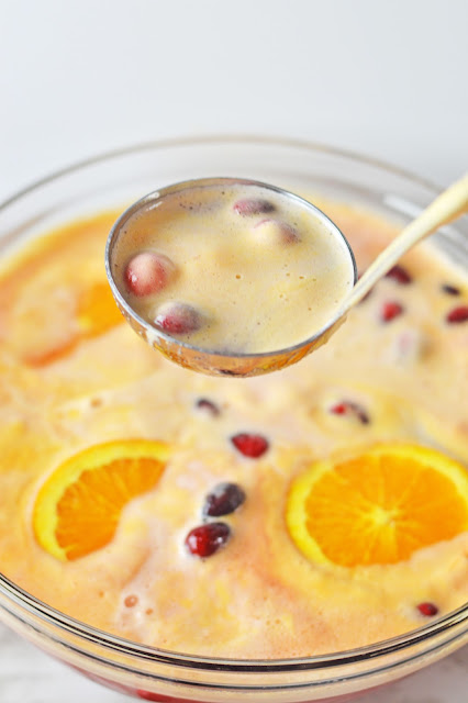 punch in a ladle over a glass punch bowl.