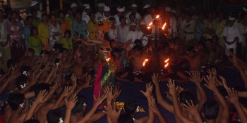 A group of men performing the Kecak Dance in Bali. The men are dressed in traditional Balinese clothing and they are chanting and making rhythmic sounds. The dance is a popular tourist attraction and it is a great way to experience Balinese culture.