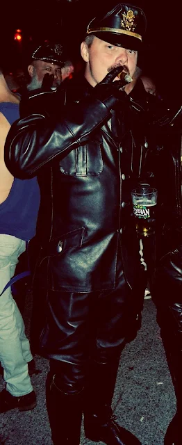 Leathermen wearing full black gear puffing cigar outside