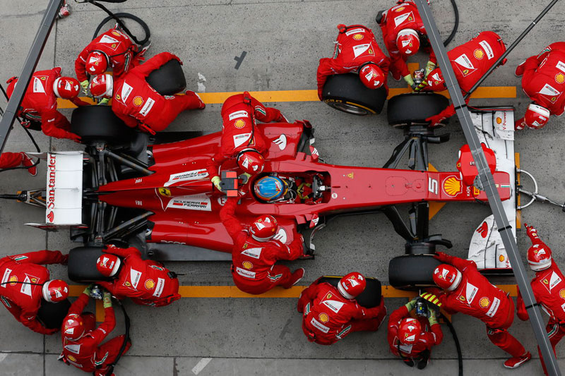 Equipo Ferrari en boxes trabajando en equipo para cambiar neumáticos
