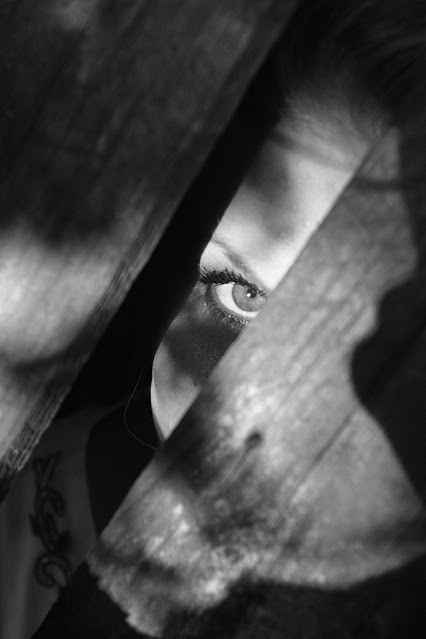 grayscale-photo-of-woman-peeking-on-planks