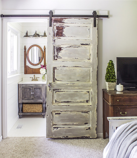 five panel vintage door is converted into a sliding barn door for bathroom in master bedroom