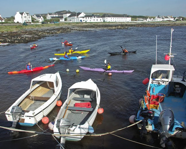kayakers and moored boats in the harbour in front of Bruichladdich Distillery