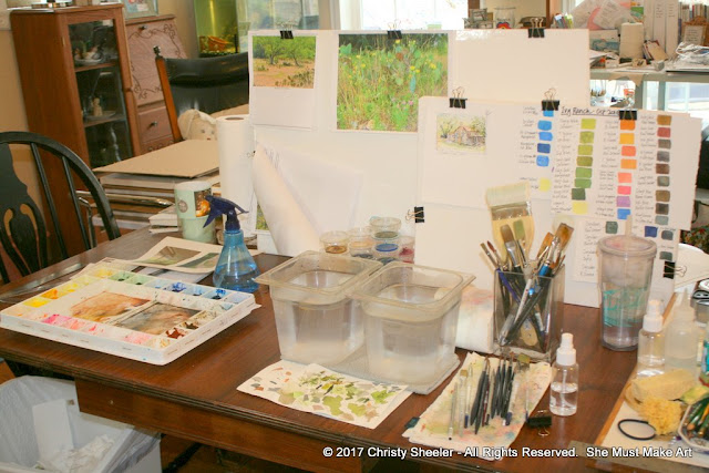 A glance at my art table, filled with palettes, water containers and brushes.