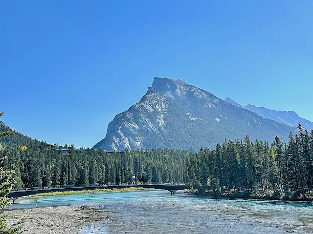Scenic view of Bow River flowing beneath the iconic bridge,  across from Banff Town