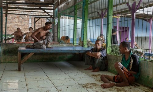 Para pasien sedang santai dan ngobrol bersama di aula yang tampak kotor dan bau anyir