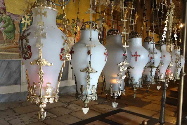 A l'entrée de la Basilique, les huit lampes suspendues au-dessus de la pierre de l'onction